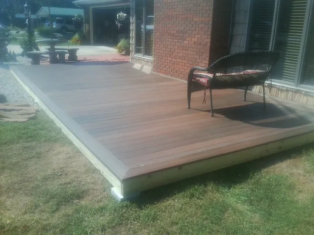 New wood deck and wicker chair beside a brick house in Rayville
