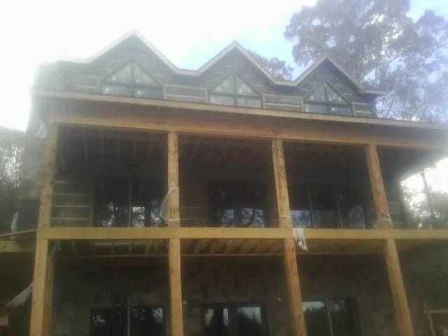 Dormers and porch framing on a large log home under construction — Roof Coating work by our crew in Rayville