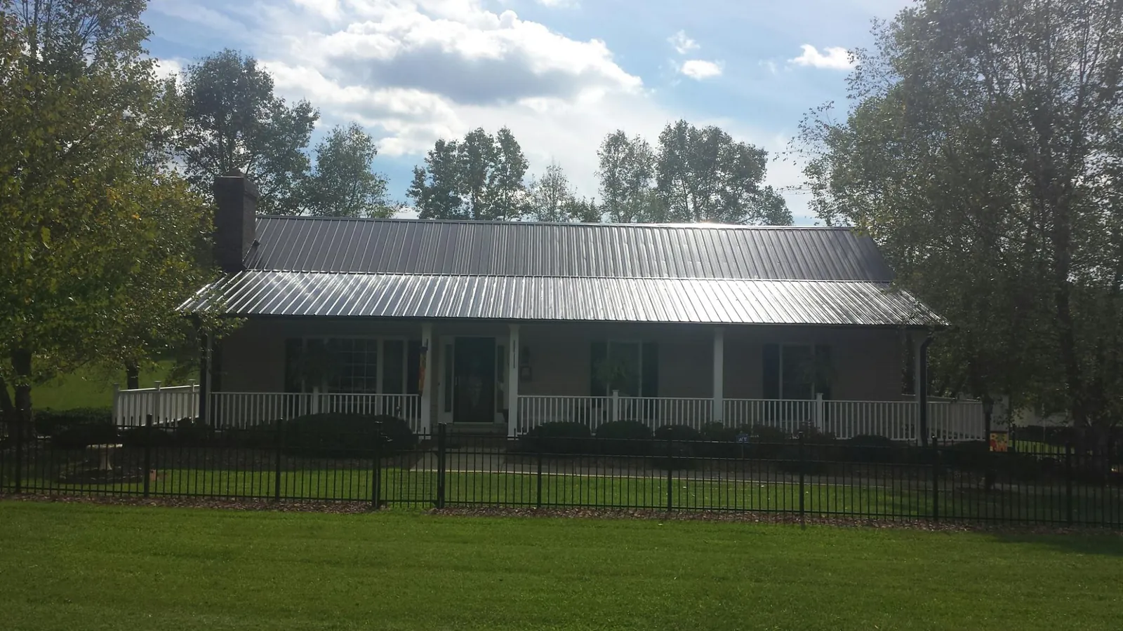 Gray metal roof on a brick ranch with a full width front porch — Gutter Guard Installation work by our crew in Rayville