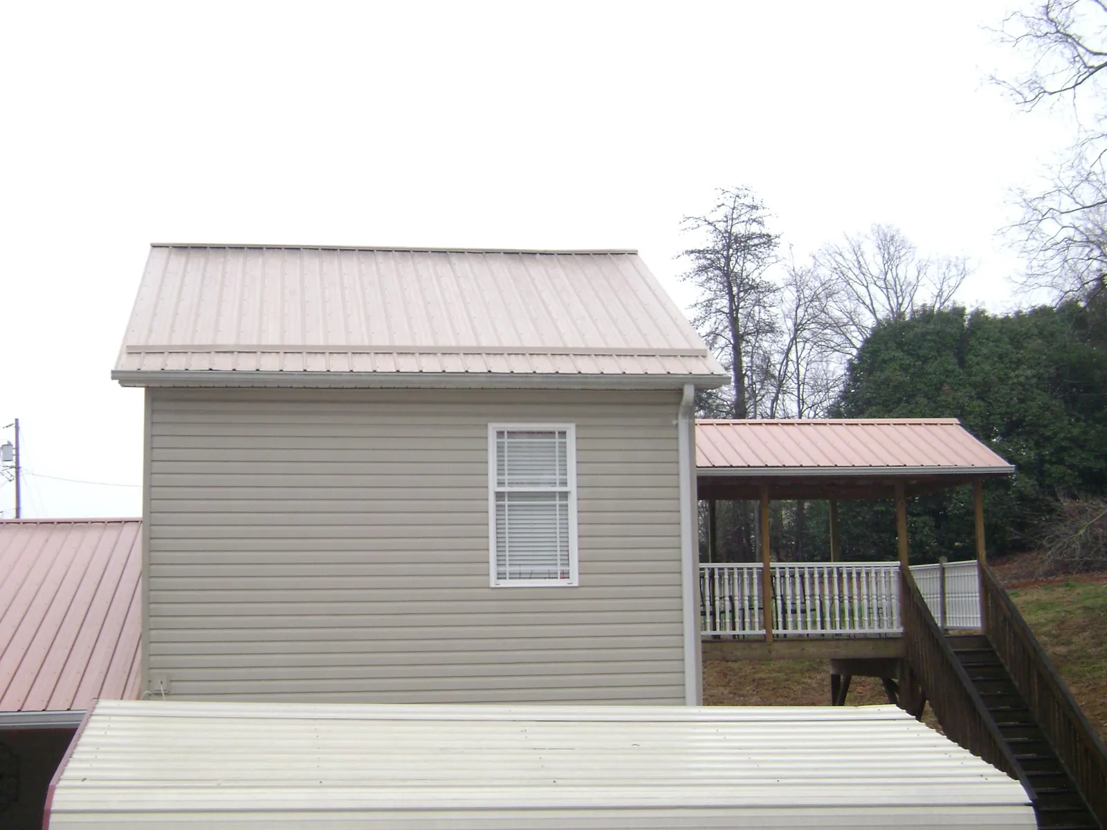Tan metal roofs on a two story addition and attached porch, from a Roof Replacement job in Rayville