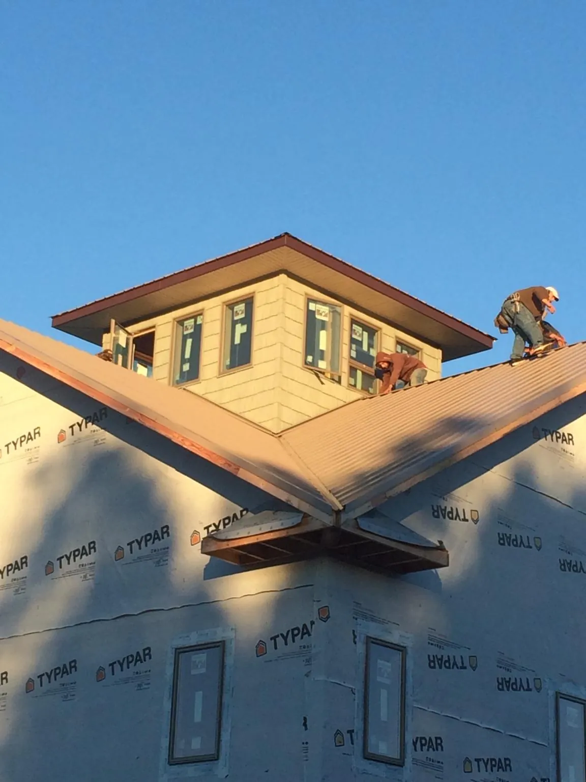 Roofers working around a rooftop cupola on a new metal roof at sunset — Roof Waterproofing in Rayville by Roofing Brothers